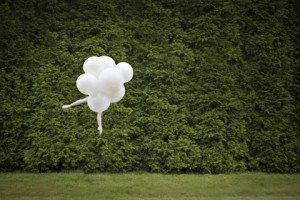ballet dancer floating with baloons over greenery