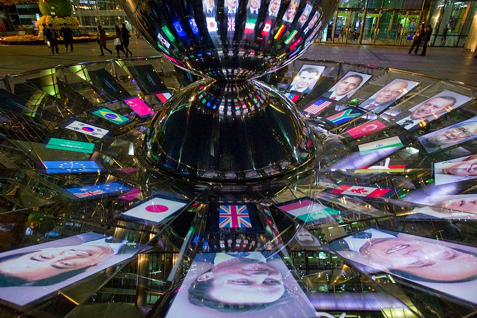 Seoul, Korea — The faces of G-20 leaders are projected onto a mirrored revolving sculpture.