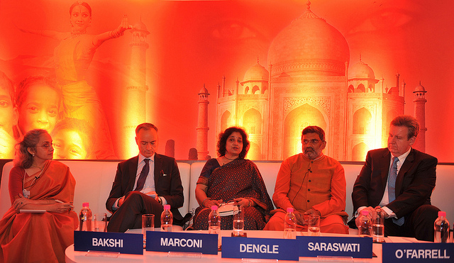 an economics summit in India with a background of fiery red lighting the taj mahal and tantric symbology